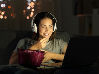 woman with a bowl of popcorn watching a movie online